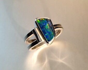 May include: A silver ring with a blue and green opal gemstone set in a shield-shaped setting.