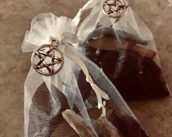 May include: Two white mesh bags filled with various stones and crystals. Each bag has a silver pentagram charm attached.