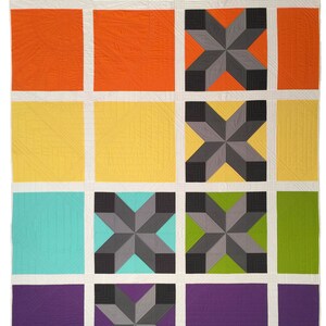 May include: A colourful quilt with a geometric design. The quilt is made up of squares of different colours, including red, orange, yellow, green, blue, and purple. Each square has a different pattern, including stars, stripes, and diamonds.