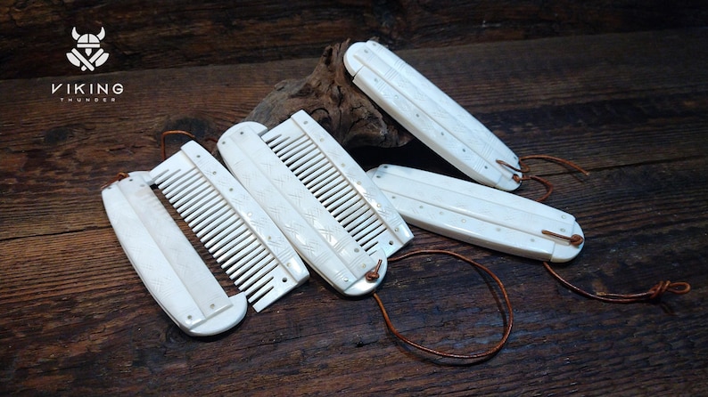 May include: Ivory-coloured Viking combs with detailed carvings and leather cords. The combs are arranged on a dark wooden surface, highlighting their intricate design and craftsmanship. The Viking Thunder logo is in the upper left corner.