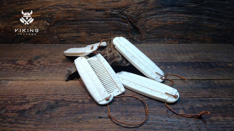 May include: Several white combs and grooming tools with leather straps, displayed on a rustic wooden surface. The Viking Thunder logo is in the top left corner. The combs are rectangular in shape.