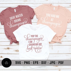 Puede incluir: Tres camisetas blancas con texto rosa. La primera camiseta dice "Save Water Drink Champagne". La segunda camiseta dice "You Had Me At Champagne". La tercera camiseta dice "Pop The Champagne I Am Changing My Last Name".