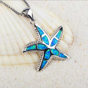 May include: A silver necklace with a blue opal starfish pendant. The pendant is made of silver and has a detailed design.