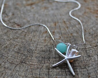 May include: A silver chain necklace with a starfish charm, a light blue bead, and a pink pearl.