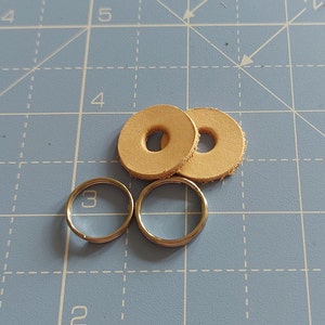 May include: Two tan leather rings with a hole in the centre, and two silver key rings.