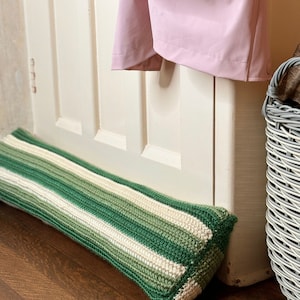 May include: A green and white striped crocheted doorstop. The doorstop is made of yarn and is a great way to keep drafts out of your home.