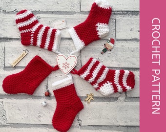 May include: Four crocheted Christmas stockings in red and white stripes. Two stockings are solid red, and two are red and white striped. The stockings are arranged in a circle on a white brick background.