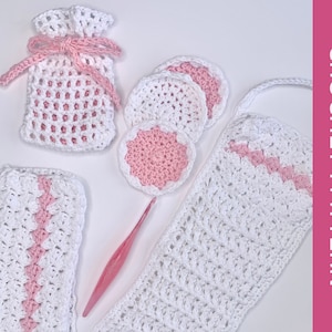 May include: A crochet pattern for a set of bathroom accessories, including a washcloth, a set of makeup remover pads, and a small bag. The items are crocheted in white and pink yarn.