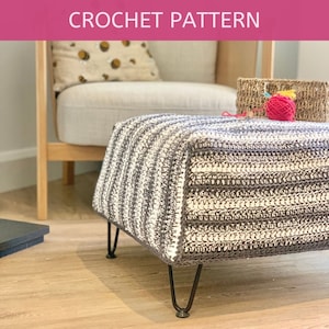 May include: A crocheted ottoman with black metal legs. The ottoman has a striped pattern in white and gray yarn.