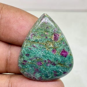 以下が含まれることがあります： 涙の形をした緑とピンクの宝石のカボション。石は緑とピンクのまだら模様をしています。