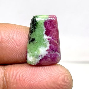 May include: A green, white and pink gemstone cabochon with a faceted shape. The gemstone is a natural stone with a unique colour pattern.
