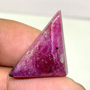 Op de afbeelding: Een driehoekige, roze robijn edelsteen met een gepolijste afwerking. De edelsteen heeft een dieproze kleur en een glad, glanzend oppervlak.