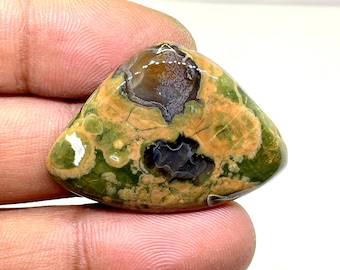 May include: A green, brown, and white moss agate cabochon with a unique pattern. The stone is smooth and polished, and it has a natural, organic look.