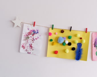Kinder-Kunstausstellungsstück mit weißen Sternen und bunten Wäscheklammern, einfach zu montierender Kinder-Papier-Bastelbügel