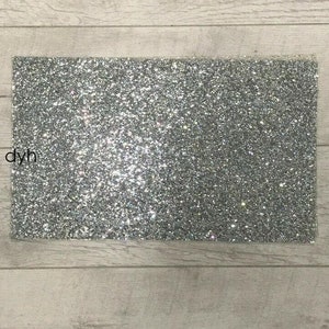 Könnte beinhalten: Ein Blatt silbernes Glitzerpapier. Das Papier ist einfarbig silber mit einem glitzernden Finish.
