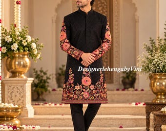Pode incluir: Um sherwani preto com gola mandarim e mangas compridas, adornado com bordados florais intrincados em tons de rosa, laranja e verde ao longo dos punhos e da bainha. A peça é combinada com calças pretas lisas.