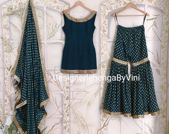 Può includere: Un set salwar kameez blu turchese con ricami dorati. Il set comprende una kameez a maniche corte, pantaloni svasati e una dupatta abbinata. La dupatta ha un motivo a pois dorati.