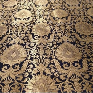 May include: Black fabric with a gold brocade pattern featuring intricate floral designs. The fabric has a luxurious and traditional look.
