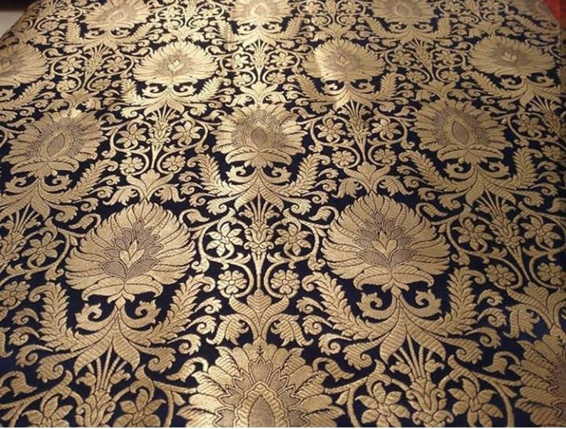 May include: Black fabric with a gold brocade pattern featuring intricate floral designs. The fabric has a luxurious and traditional look.