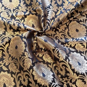 May include: Black fabric with a gold floral brocade pattern. The fabric is woven with a raised design, creating a textured look.