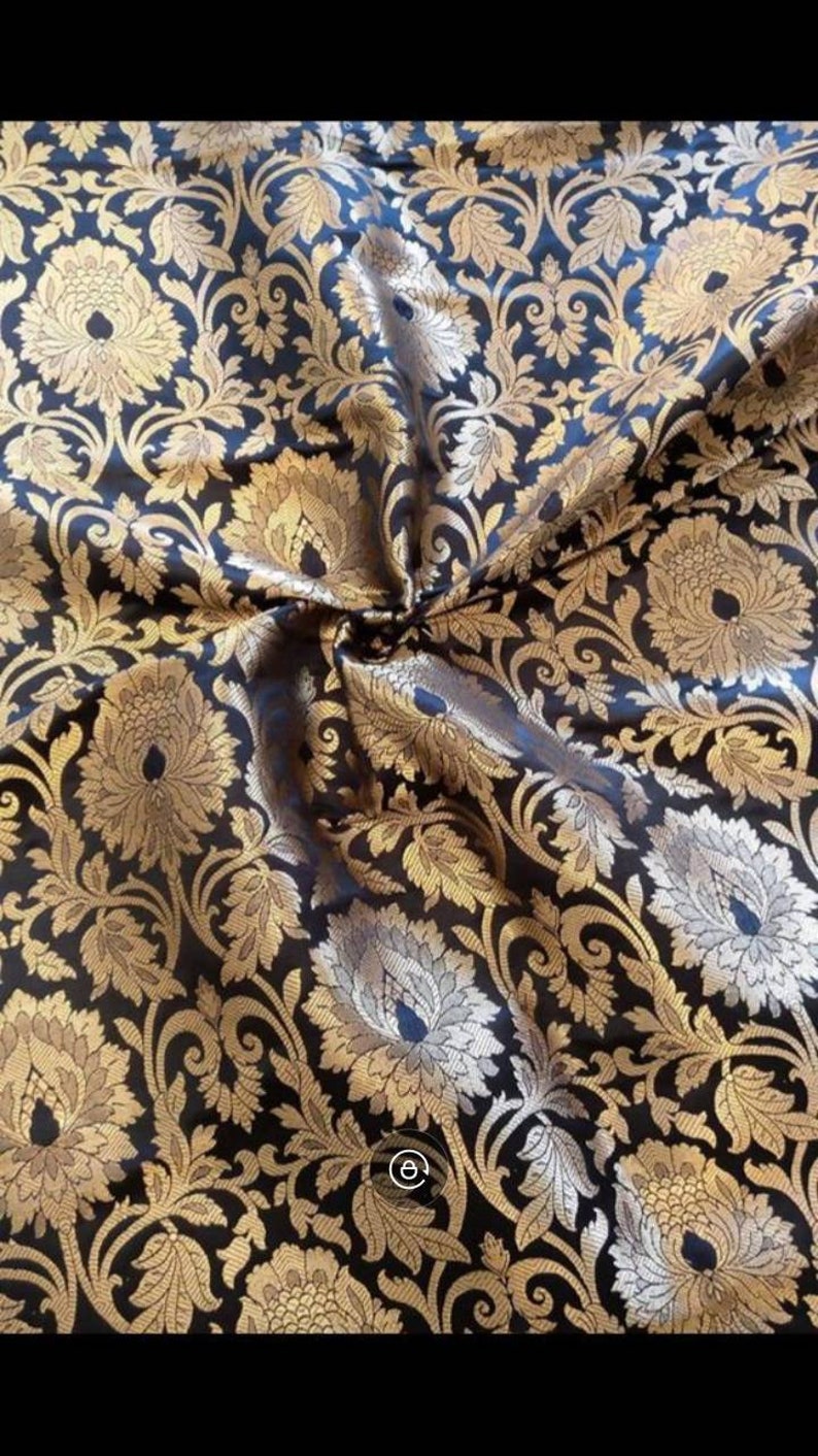 May include: Black fabric with a gold floral brocade pattern. The fabric is woven with a raised design, creating a textured look.
