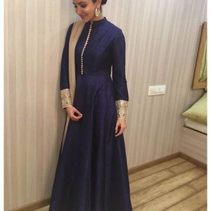May include: A navy blue long-sleeved dress with a high neckline and a button closure. The dress has gold embroidery on the cuffs and a matching gold dupatta.
