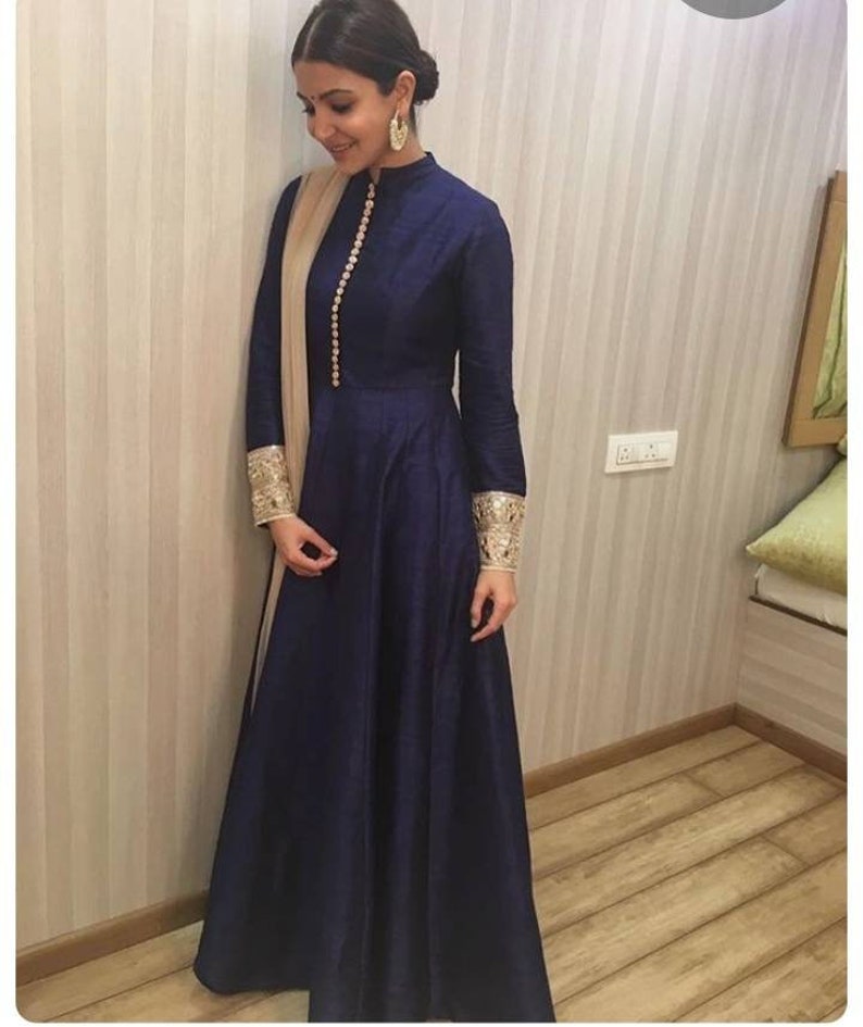 May include: A navy blue long-sleeved dress with a high neckline and a button closure. The dress has gold embroidery on the cuffs and a matching gold dupatta.