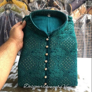 Puede incluir: Una kurta azul turquesa con un patr&oacute;n floral y botones dorados. La kurta tiene un cuello mandar&iacute;n y est&aacute; bordada con peque&ntilde;as lentejuelas.