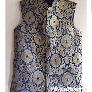 May include: A sleeveless vest with a blue background and a gold floral pattern. The vest has a mandarin collar and a button closure.