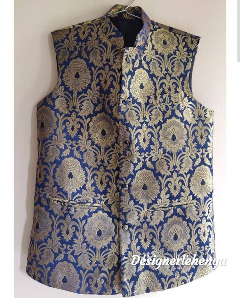 May include: A sleeveless vest with a blue background and a gold floral pattern. The vest has a mandarin collar and a button closure.