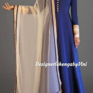 May include: A royal blue long-sleeved dress with a high neckline and a row of gold buttons. The dress has a flared skirt and is paired with a sheer white dupatta with a gold and black border.