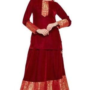 May include: A maroon velvet kurta and skirt set with gold embroidery. The sleeves and bottom of the skirt have a gold and red brocade trim.