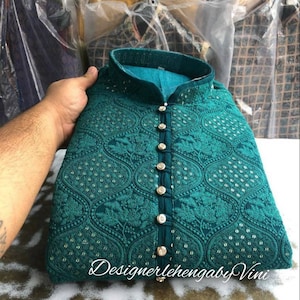 Puede incluir: Una kurta azul turquesa con cierre de botones en la parte delantera y bordados intrincados. La kurta tiene un cuello alto y est&aacute; decorada con peque&ntilde;as lentejuelas plateadas.
