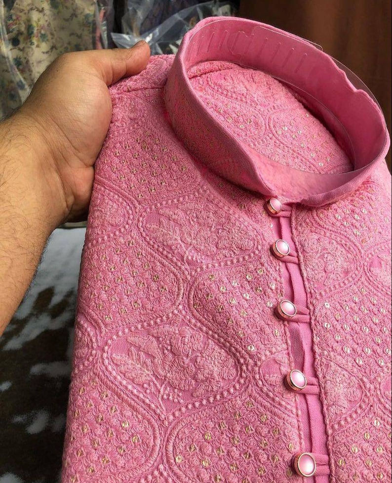 Puede incluir: Una kurta bordada de color rosa con cuello alto y cierre de botones. La tela tiene un delicado patr&oacute;n floral y est&aacute; adornada con peque&ntilde;as lentejuelas.