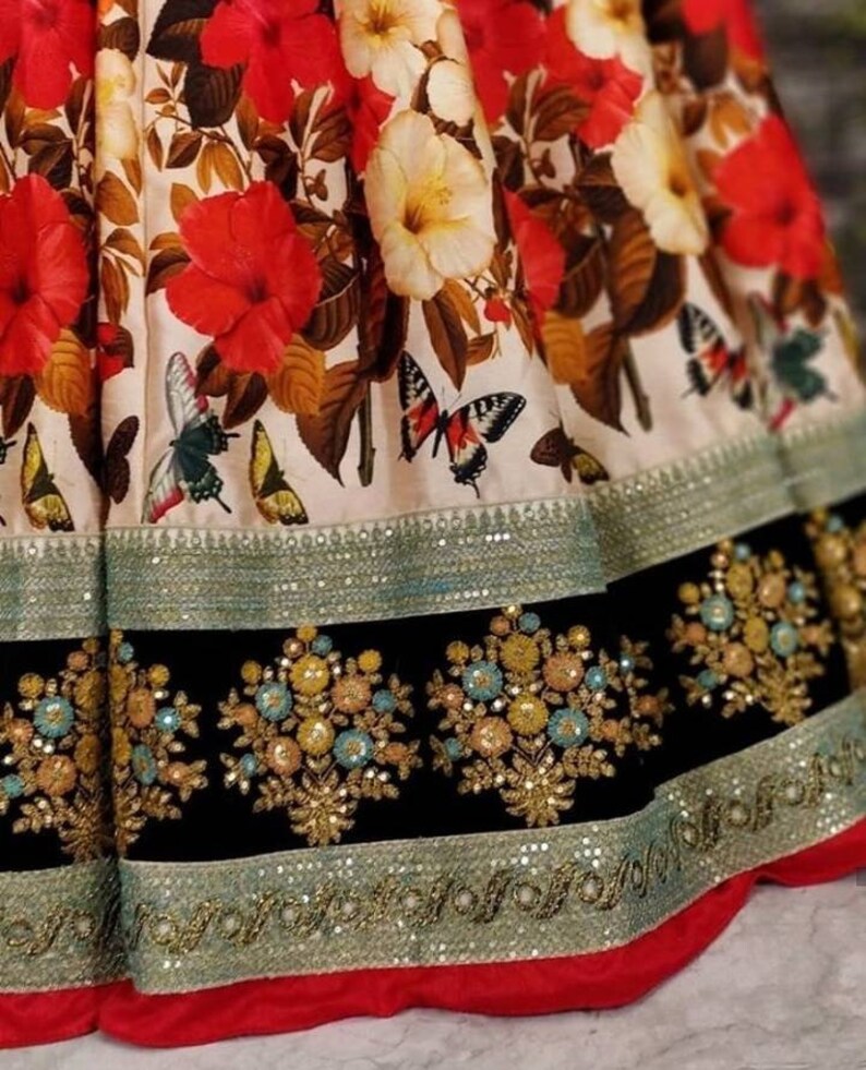 Pu&ograve; includere: Una gonna con stampa floreale bianca e rossa con un bordo nero e argento. La gonna ha uno strato di paillettes e ricami intorno al fondo.