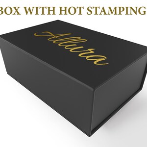 May include: A black rectangular box with a hinged lid. The box has gold lettering that reads "Allura" on the top. The text "BOX WITH HOT STAMPING" is above the box.