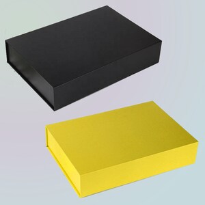 May include: Two rectangular gift boxes. The top box is black, and the bottom box is yellow. Both boxes have a magnetic closure. The boxes are empty and ready to be filled with gifts. The boxes are made of cardboard.