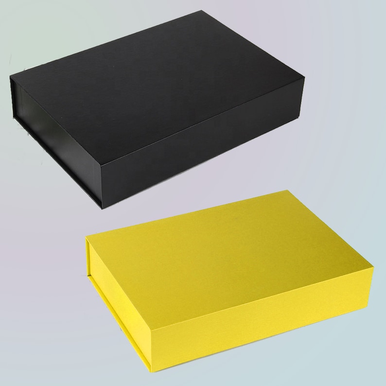May include: Two rectangular gift boxes. The top box is black, and the bottom box is yellow. Both boxes have a magnetic closure. The boxes are empty and ready to be filled with gifts. The boxes are made of cardboard.