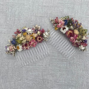 May include: Two hair combs with dried flowers. The combs are clear plastic and the flowers are a mix of pink, purple, white, and yellow.