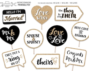 Könnte beinhalten: Eine Sammlung von Requisiten für eine Hochzeits-Fotobox mit goldenen Glitzerakzenten. Die Requisiten umfassen Schilder mit Sätzen wie "Love Wins", "Here Come the Brooms" und "Hello I'm Married". Ideal für eine Hochzeits- oder Verlobungsfeier.