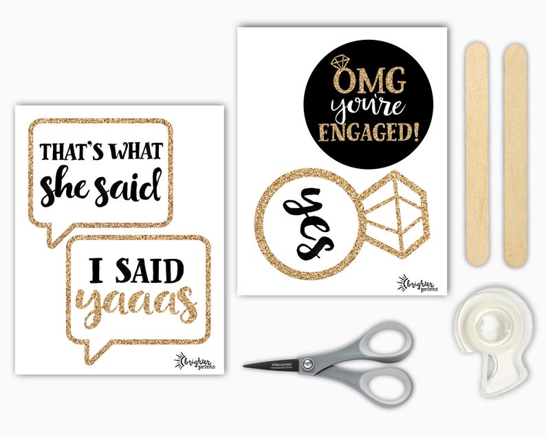 Op de afbeelding: Een set fotobooth-rekwisieten voor een verlovingsparty met gouden glitteraccenten. De rekwisieten omvatten twee spraakballonnen met de tekst "That's what she said" en "I said yaaaas", een ronde zwarte cirkel met de tekst "OMG you're engaged!" en een ring met een diamant en het woord "yes" in gouden glitter. De set bevat ook twee houten stokjes, een schaar en een rol tape.