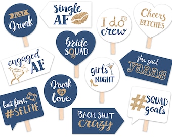 May include: A set of 12 blue and white photo booth props with gold glitter accents. The props feature phrases like "Just Drunk", "Single AF", "I Do Crew", "Bride Squad", "Engaged AF", "Drunk in Love", "But First, #Selfie", "Girls Night", "She Said Yaas", "Cheers Bitches", "#Squad Goals", and "Bach Shit Crazy".