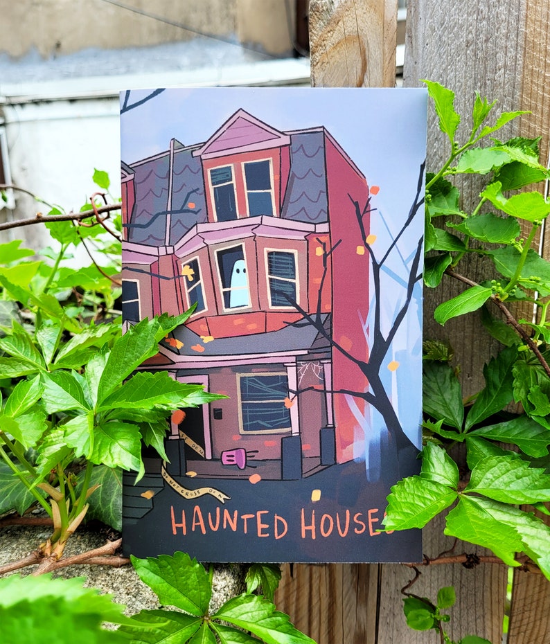 May include: A black and white illustration of a haunted house with a ghost in the window. The house is red with white trim and has a porch with a door. The text "Haunted House" is printed below the house.