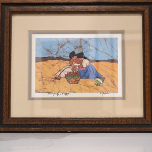 May include: Framed artwork depicting two figures in a field, with a blue and yellow background. The figures are near a basket of red items. The artwork is in a dark brown wooden frame.