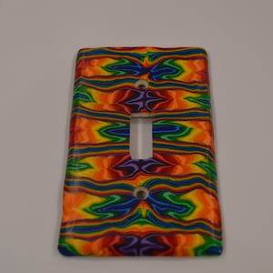 May include: A light switch cover with a colorful abstract design featuring shades of red, orange, yellow, green, blue, and purple.