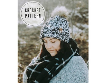 May include: A black and white crocheted beanie with a white pom pom on top. The beanie is worn by a person with a black and white plaid scarf and a gray sweater. The image has the text "CROCHET PATTERN" in a circle.