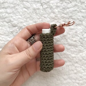 Pu&ograve; includere: Un porta-balsamo per labbra in crochet verde con un portachiavi in oro rosa. Il porta-balsamo &egrave; realizzato con una maglia testurizzata ed &egrave; progettato per adattarsi a un tubo di balsamo per labbra di dimensioni standard.