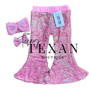 Puede incluir: Pantalones acampanados de lentejuelas rosas y diadema a juego con lazo. Los pantalones tienen una cintura elástica rosa y las palabras "Teeny Texan Boutique" están impresas en los pantalones.