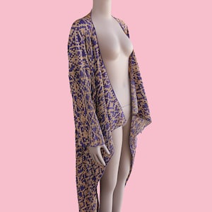 May include: A long, purple and gold patterned cardigan with a draped, asymmetrical hem.
