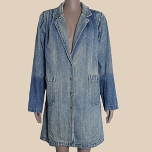 May include: A long, light blue denim jacket with a button closure and two front pockets.